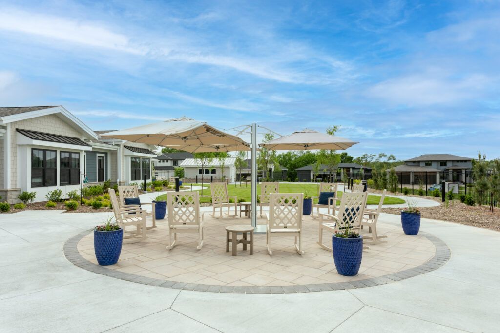 A tranquil outdoor seating area with chairs and a table surrounded by potted plants under a clear blue sky.