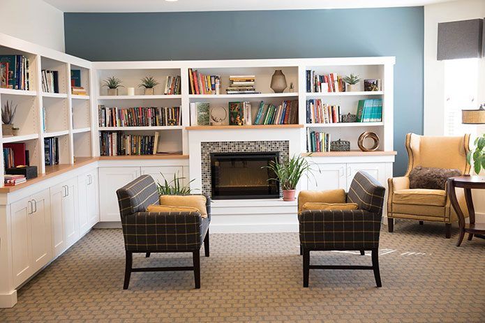 A cozy living room with bookshelves, a fireplace, and comfortable chairs.