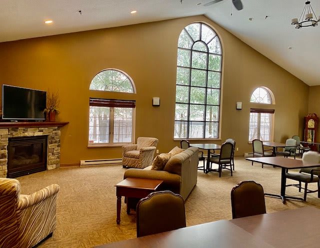 A spacious living room with high ceilings, large windows, and cozy seating arrangements near a fireplace.