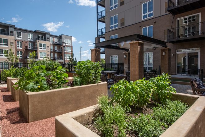 A modern apartment complex featuring an urban garden and outdoor seating area.