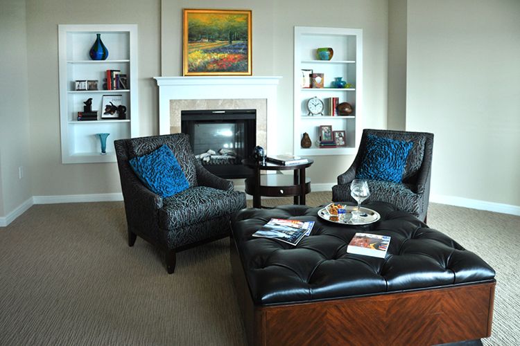 A cozy living room featuring stylish armchairs, a fireplace, and elegant shelving with decorative items.