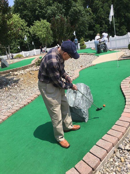 A man playing mini-golf outdoors.