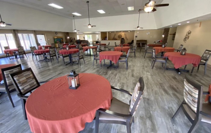 An empty dining area with tables covered in red tablecloths.