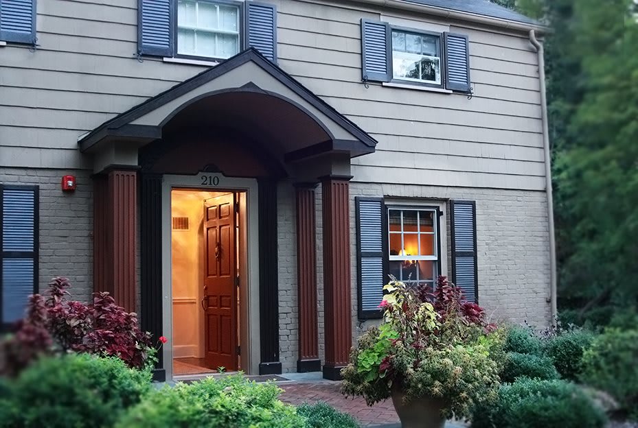A welcoming house with a well-lit entrance and garden in the evening.