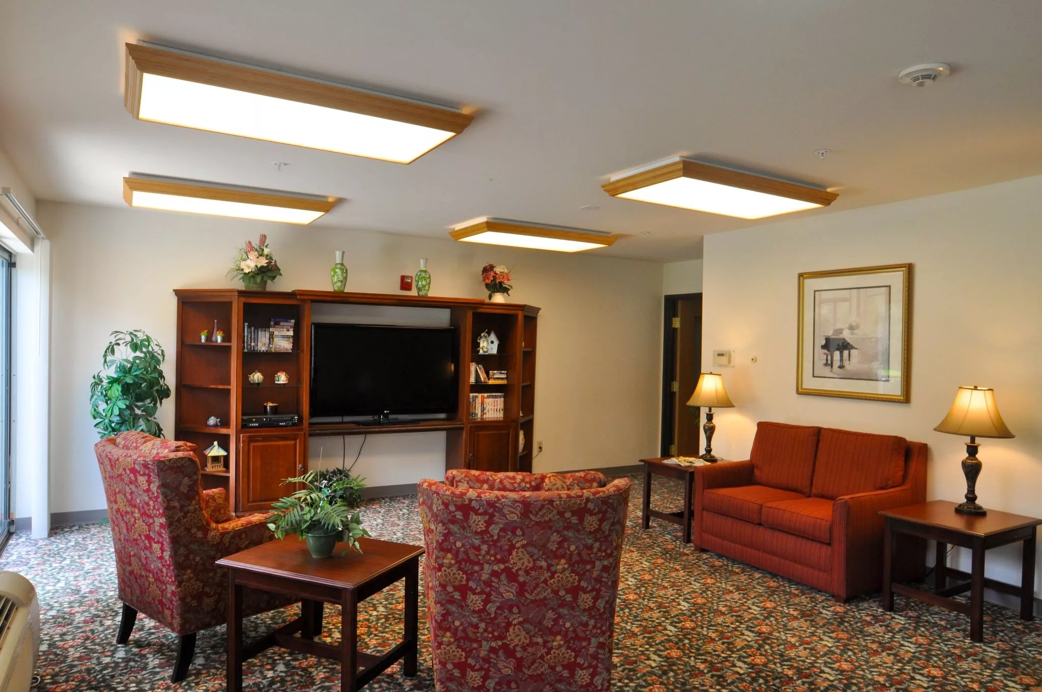 A cozy living room with a TV, shelves, and comfortable seating.