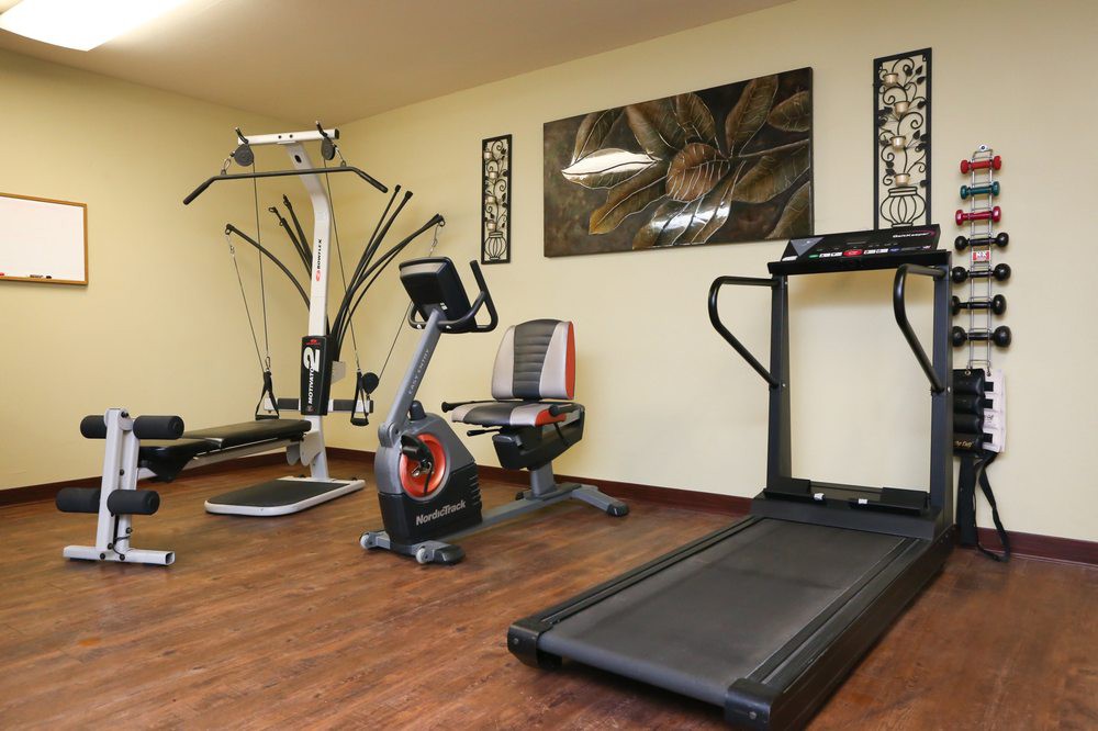 A compact home gym with various exercise equipment including a treadmill, stationary bike, and weight machine.