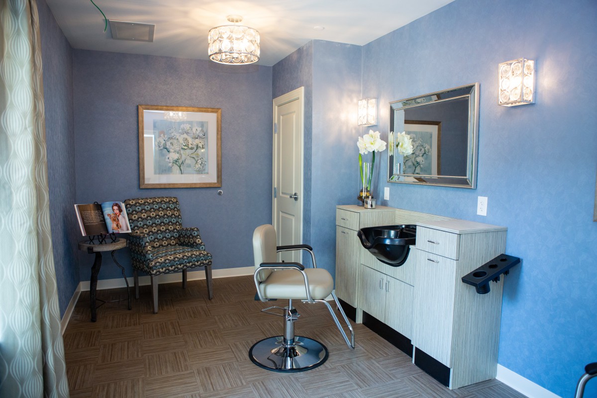 A stylish hair salon interior featuring a chair, mirror, and decorative elements.