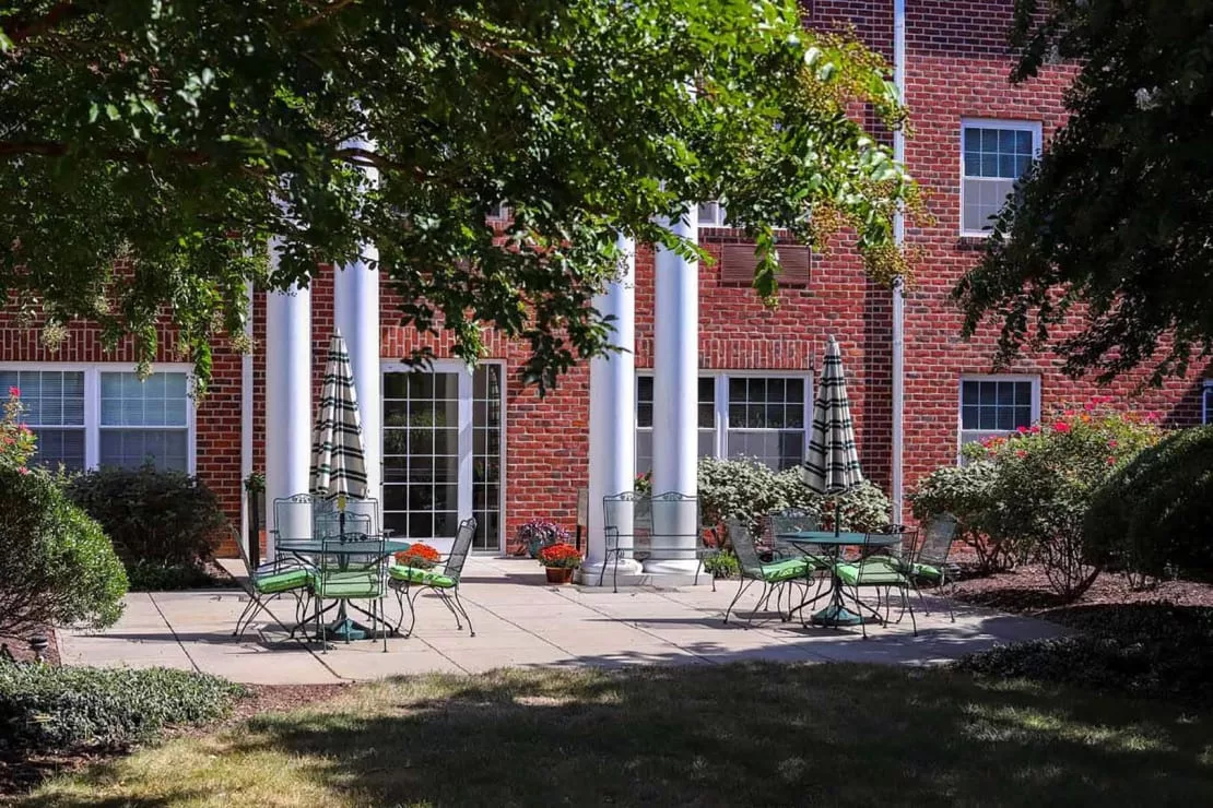 A courtyard patio with chairs and tables set up outside a brick building with large columns.