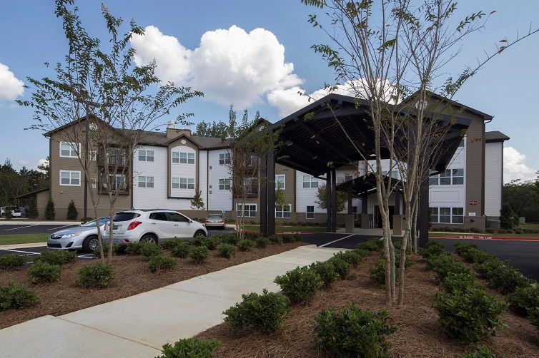 A modern residential apartment building with a covered entrance and landscaped surroundings.