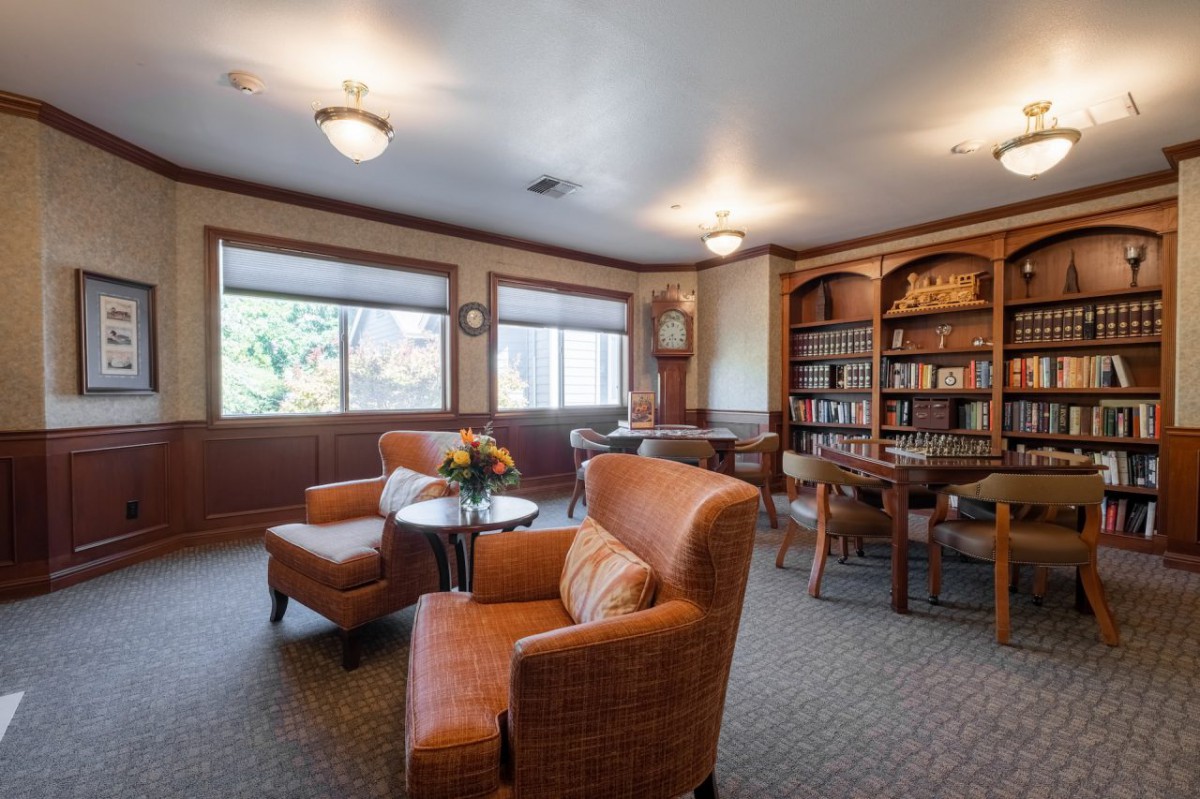A cozy library reading room with armchairs, tables, and bookshelves.
