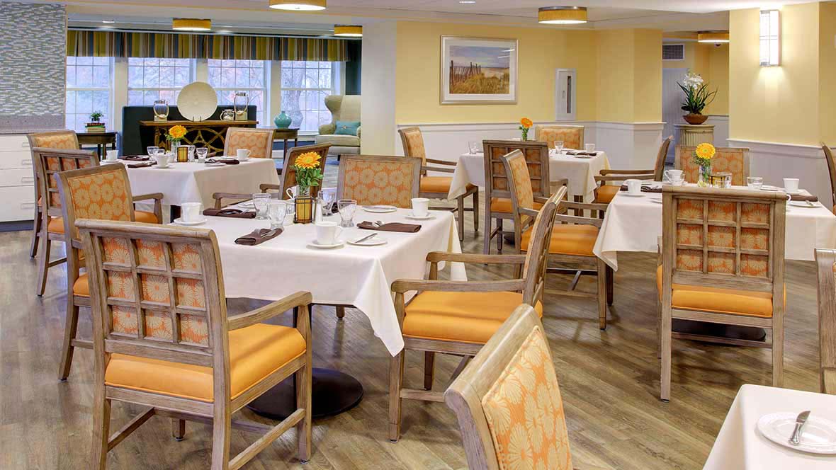 A well-arranged dining room with tables and chairs, featuring a cozy interior design.