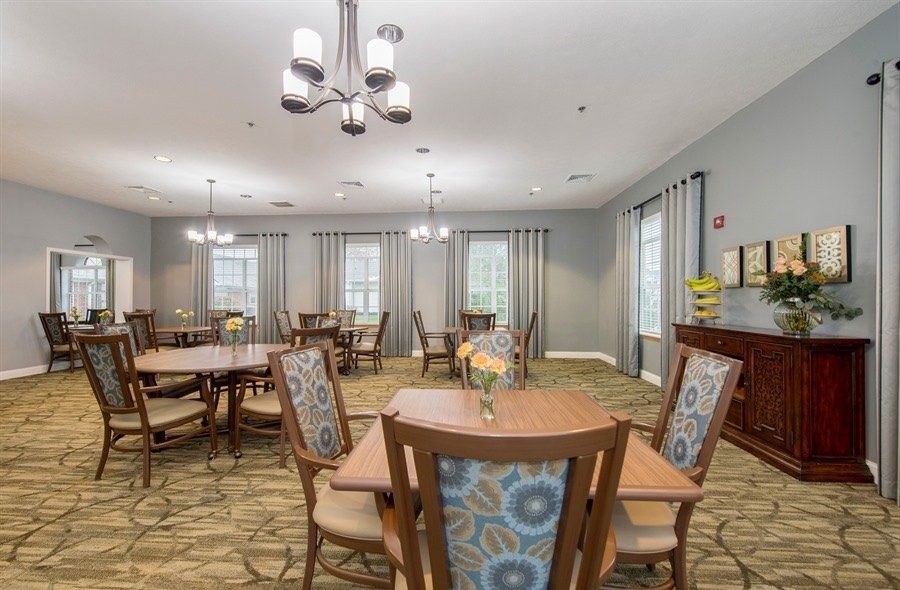 A well-lit dining area with multiple tables and chairs, featuring elegant decor and chandeliers.