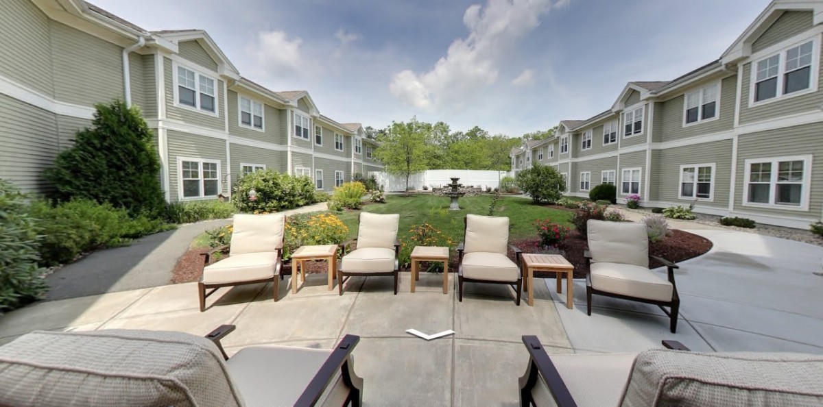 A well-maintained courtyard with comfortable outdoor seating and a central fountain, surrounded by an apartment complex.