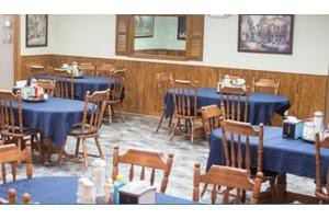 An empty restaurant dining area with wooden tables and chairs.