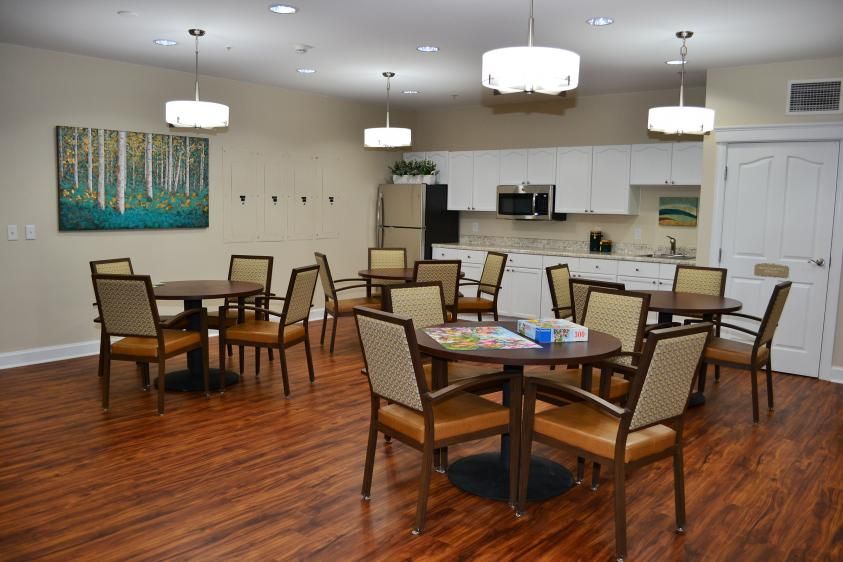 A spacious dining area with multiple tables, comfortable seating, and a kitchen space in the background.