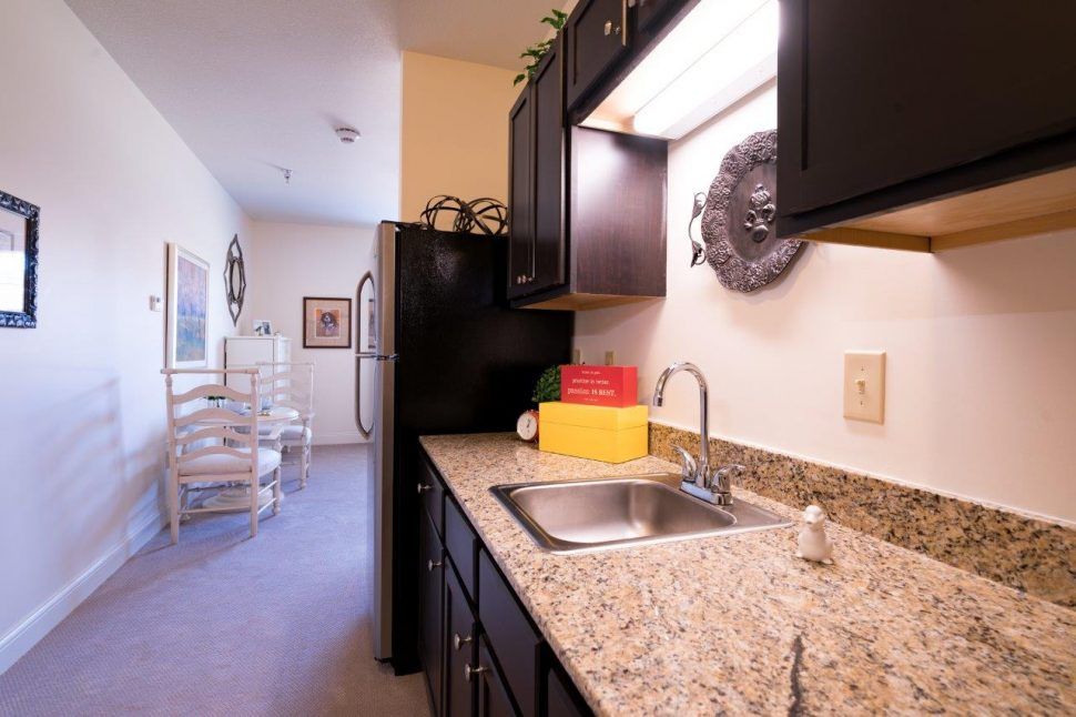 A cozy kitchen with granite countertops and dark cabinetry, leading to a small dining area.