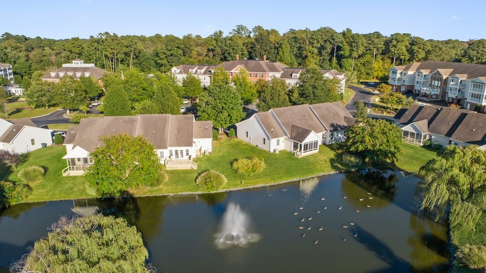 Aerial view of a serene neighborhood with houses surrounding a pond featuring a fountain.