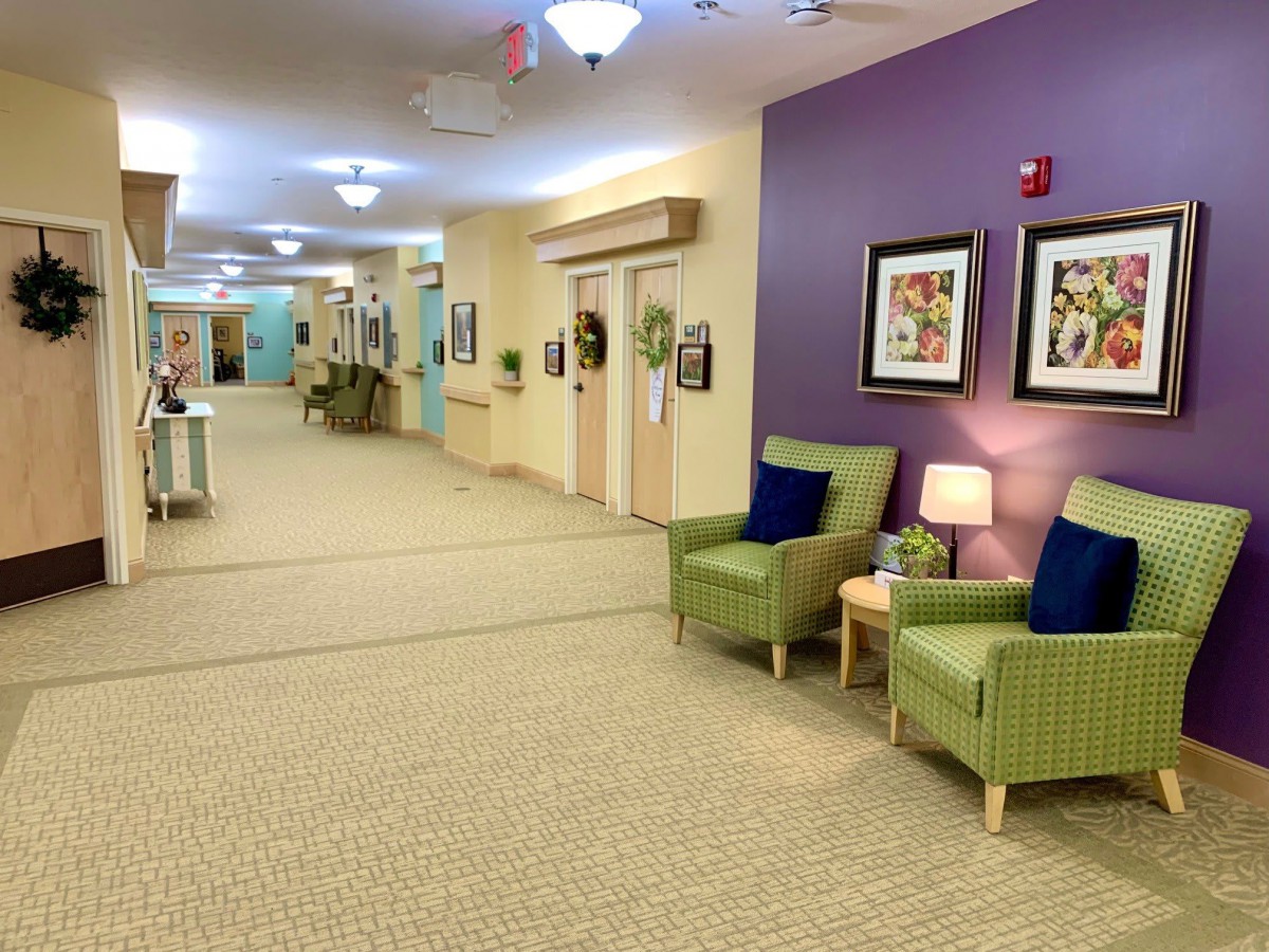 A well-lit hallway with comfortable seating and colorful artwork adorns the walls.
