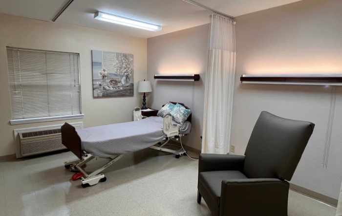A hospital room with a bed, curtain, and seating area.