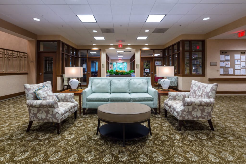 A cozy living room setup with a sofa, chairs, and a round coffee table, complemented by decorative lamps and a patterned carpet.