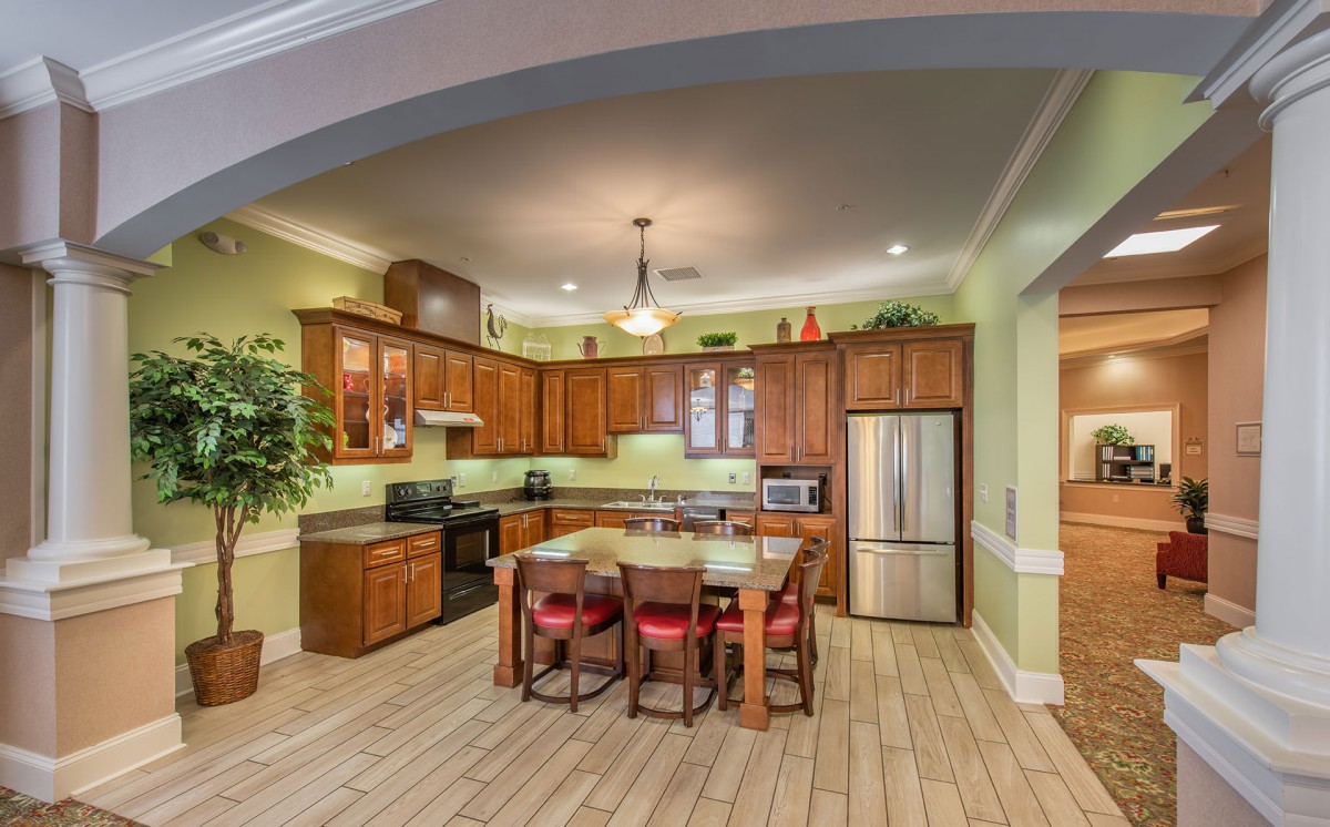 A spacious kitchen with wooden cabinets, an island with seating, and modern appliances.