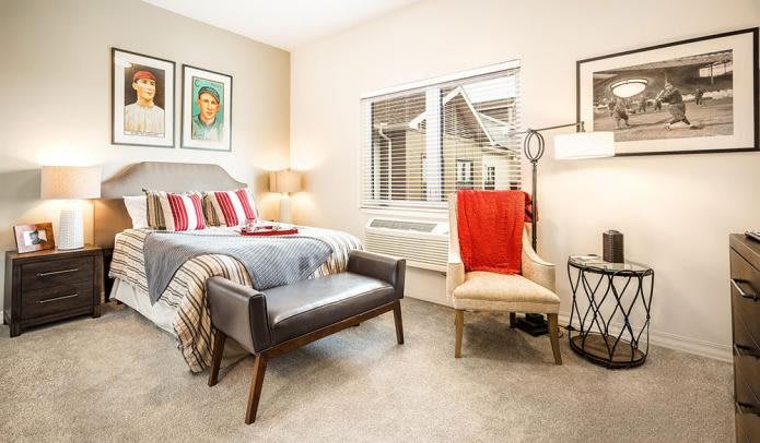 A stylish and cozy bedroom with modern decor featuring a bed, comfortable seating, and warm lighting.