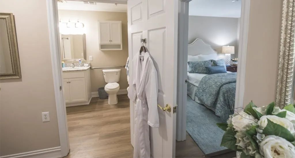 A cozy bedroom and bathroom setup with a bathrobe hanging on the door.