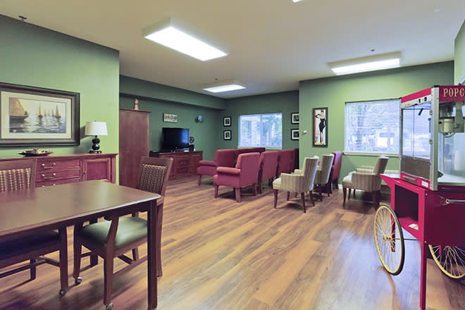 A cozy room with green walls, featuring a seating area with red chairs and a television.