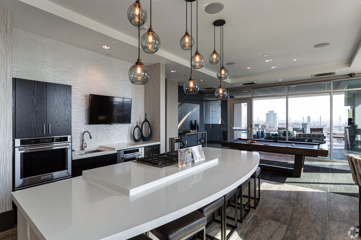 A sleek, modern kitchen with a large island and stylish pendant lights overlooking an open living space.