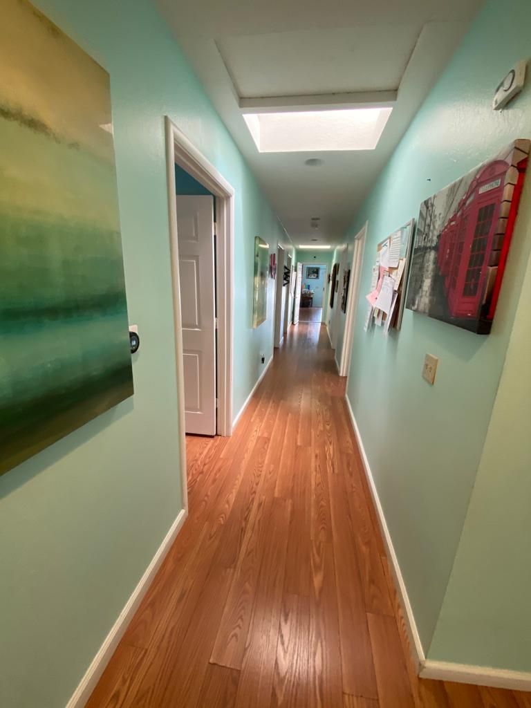 A long hallway with wooden flooring and artwork adorning the walls.
