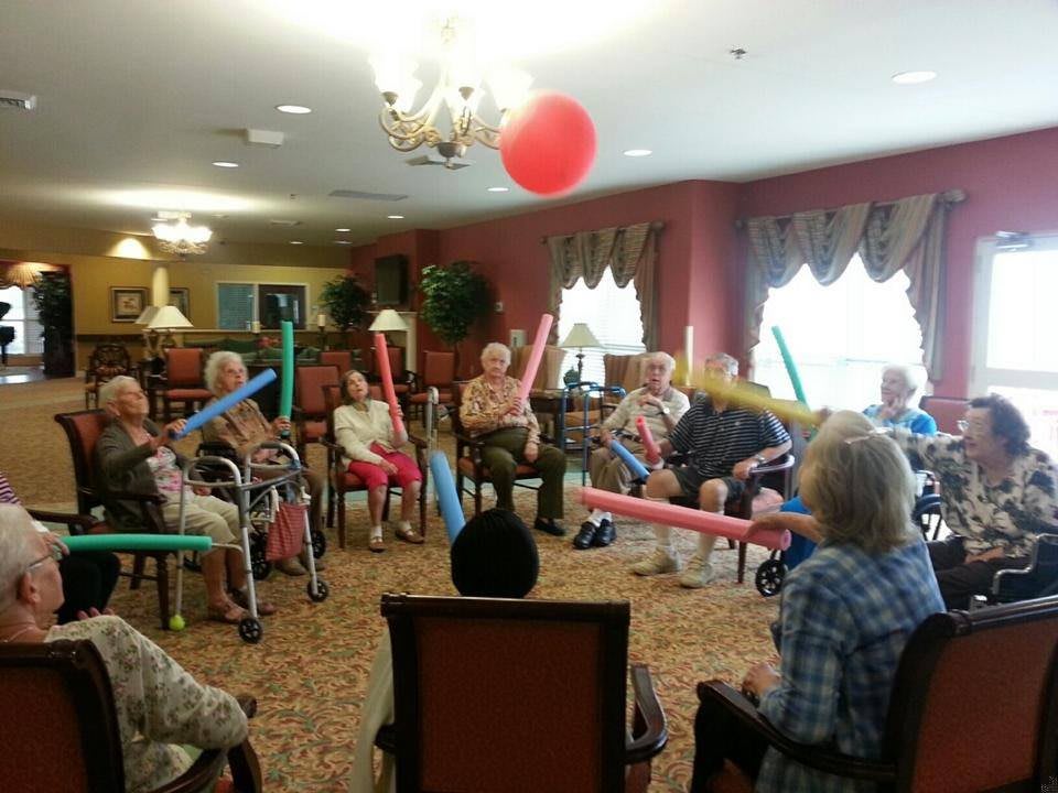 A group of elderly individuals participating in a fun indoor activity with balloons.