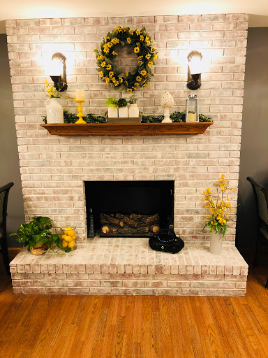 A cozy fireplace adorned with a wooden shelf, decorative plants, and warm lighting.