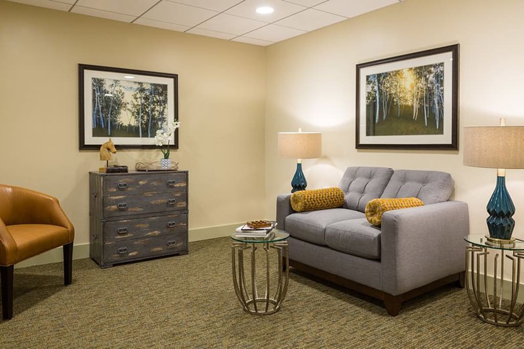 A cozy living room with a gray couch, decorative pillows, and framed artwork on the walls.