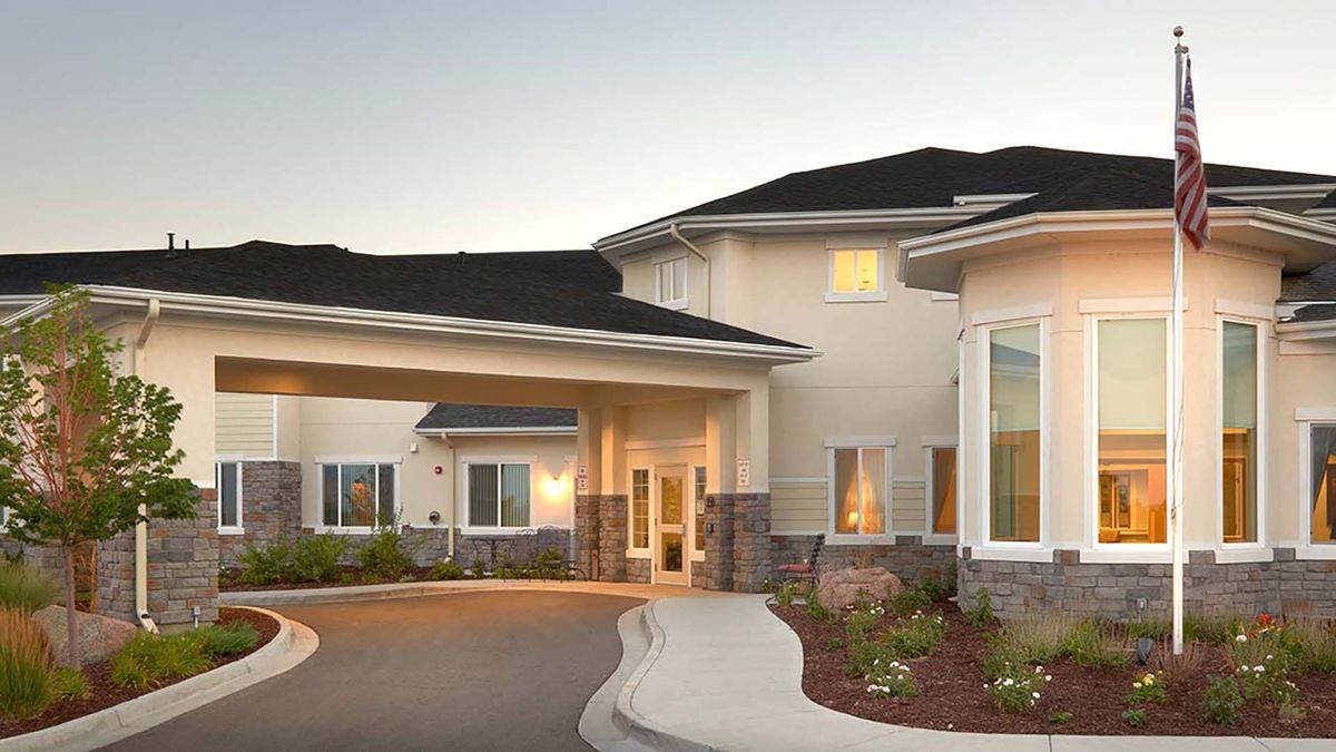 A modern residential building with a driveway and landscaped surroundings.
