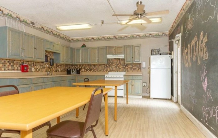 A spacious kitchen and dining area with tables, chairs, and appliances.