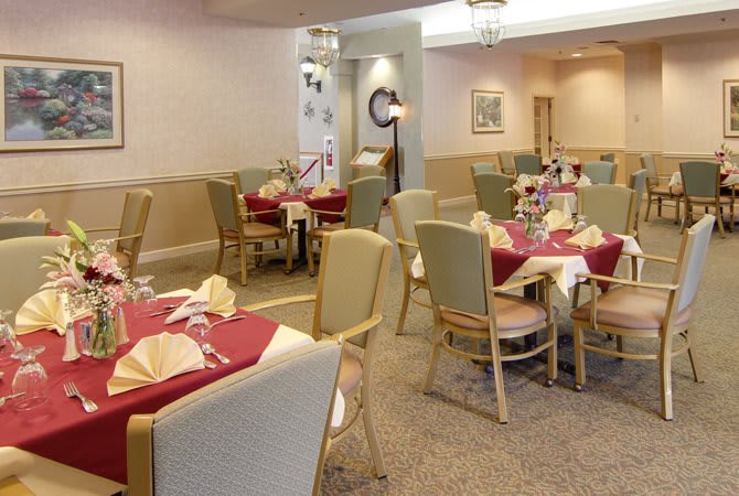 An elegantly set dining room with multiple tables and chairs prepared for service.