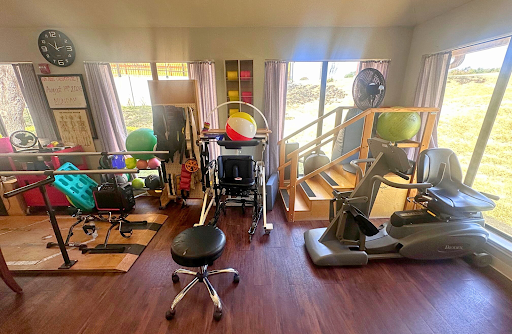 A well-equipped rehabilitation space featuring various fitness tools and a wheelchair for therapeutic exercises.