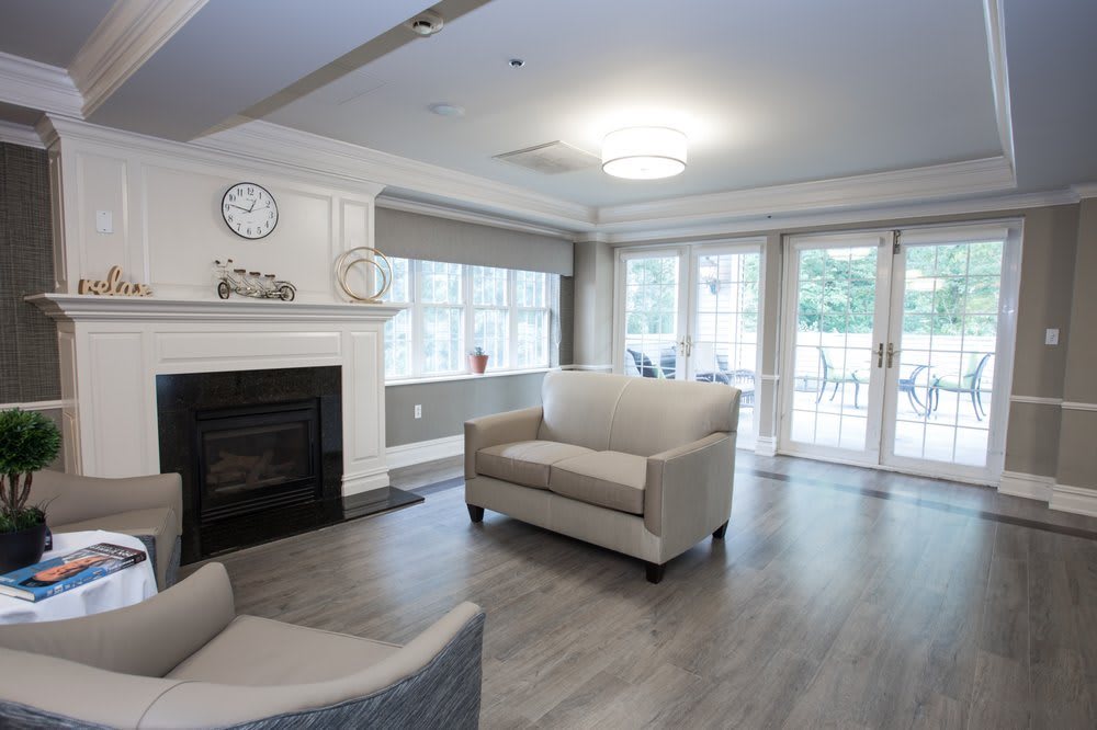 A modern living room with a fireplace and large windows, featuring comfortable sofas and a hardwood floor.