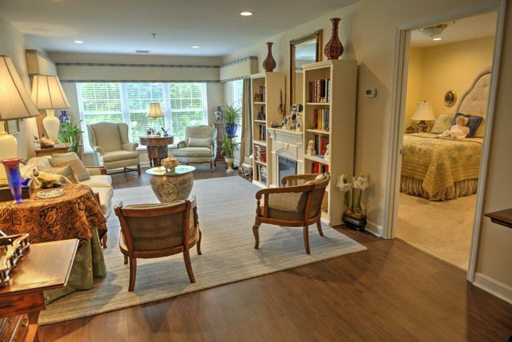 A cozy living room with comfortable seating, bookshelves, and natural light streaming through large windows.