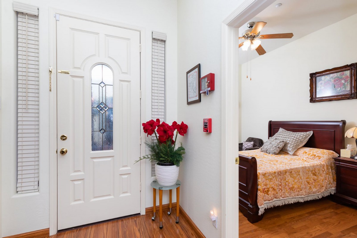 A cozy entryway with a decorative front door and a glimpse into a bedroom.