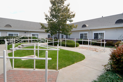 A beautifully designed accessible walkway surrounded by greenery leading to a residential building.