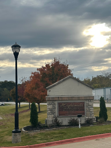 A scenic view featuring a sign amidst autumn foliage under a cloudy sky.