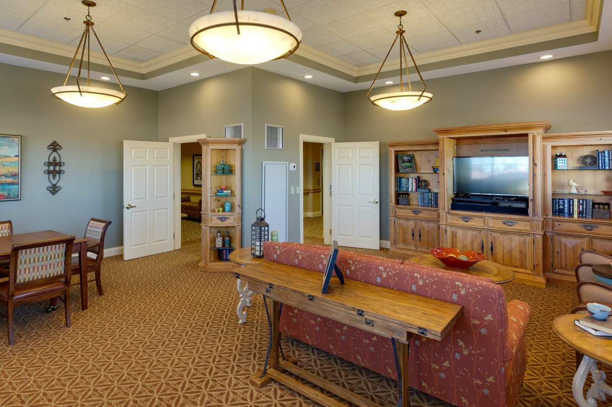 A cozy living room with a TV cabinet, shelves, and comfortable seating.