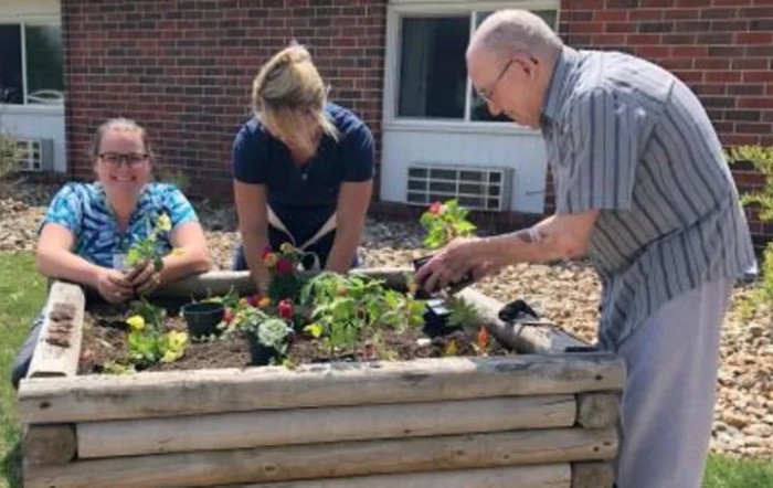 A group of people working together in a garden, planting and tending to plants.