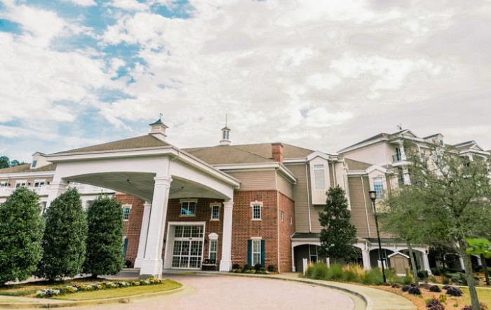 A grand building with a prominent entrance and columns under a cloudy sky.