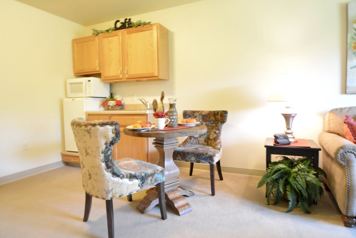 A cozy dining area with a round table and comfortable chairs adjacent to a small kitchen.