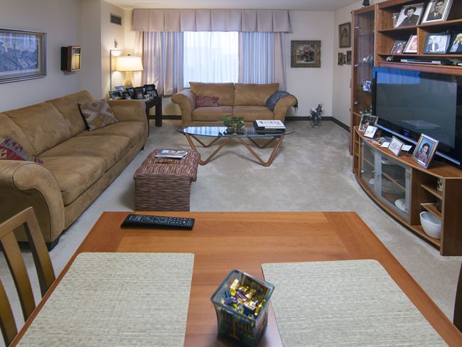 A cozy living room with comfortable seating, a television, and a well-arranged bookshelf.