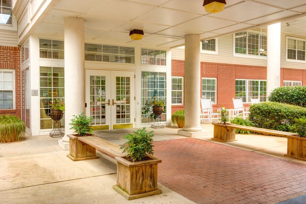 An inviting entrance with columns and benches, featuring plants for a welcoming ambiance.