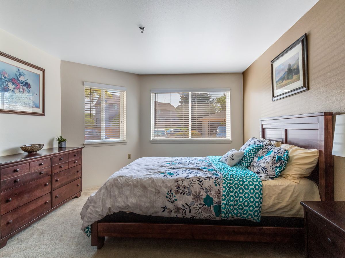 A cozy bedroom with a large bed, floral bedding, and bright natural lighting.