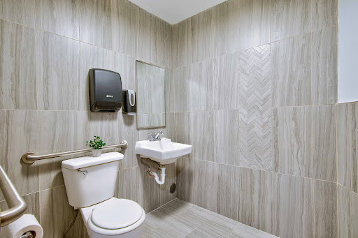 A modern bathroom featuring a toilet, sink, and soap dispenser with elegant tile work.